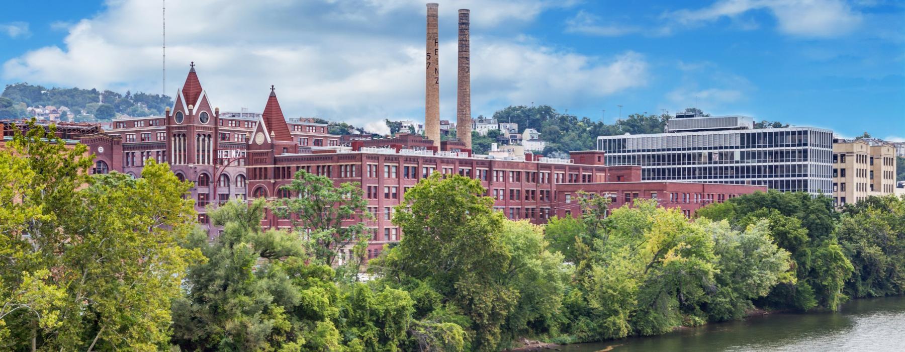 a large building with smokestacks by a river